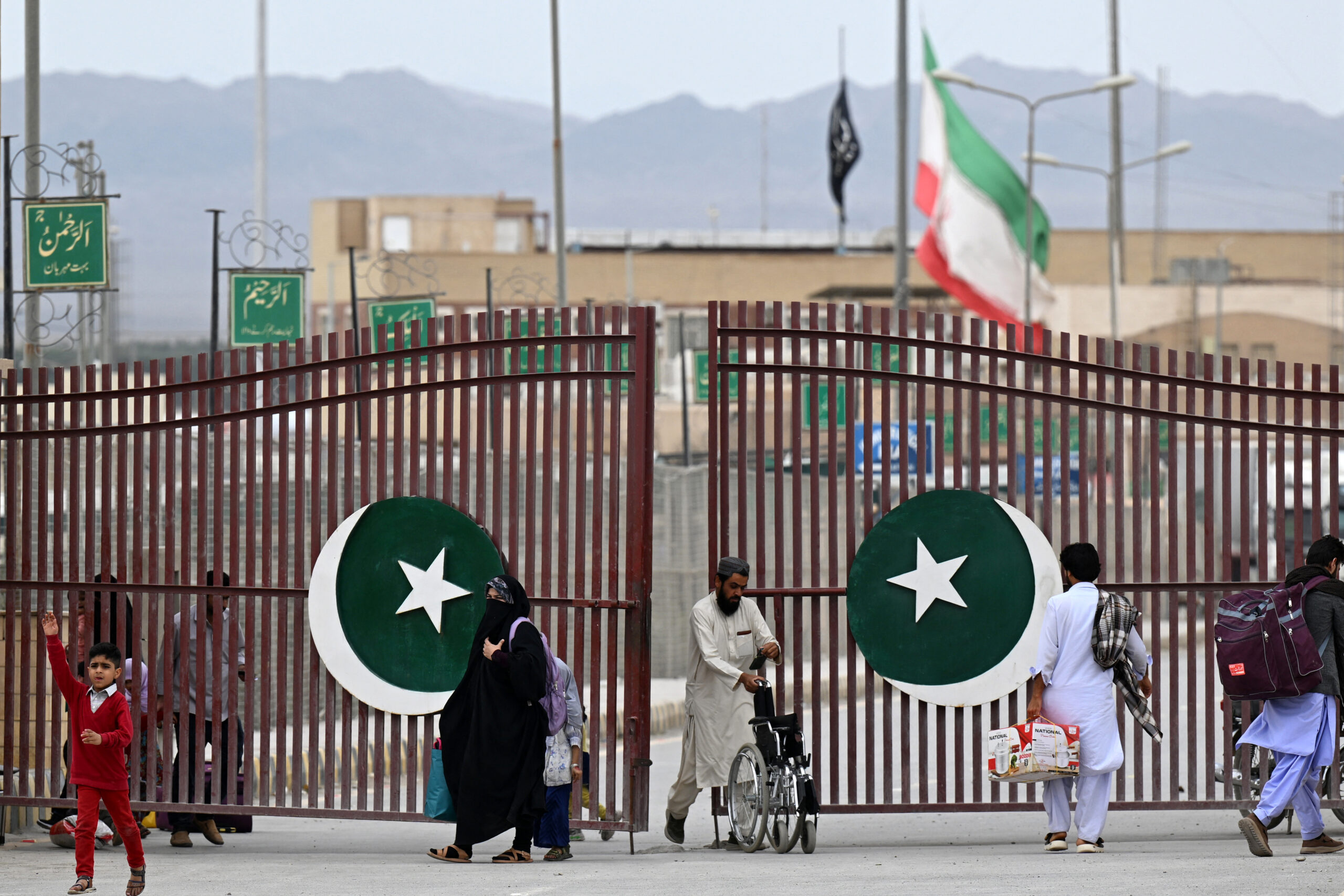 Pakistanis walk across the Taftan border as they return from Iran, in Balochistan province, on March 9, 2026 amid ongoing US-Israel strikes on Iran. (Photo by Banaras KHAN / AFP via Getty Images)