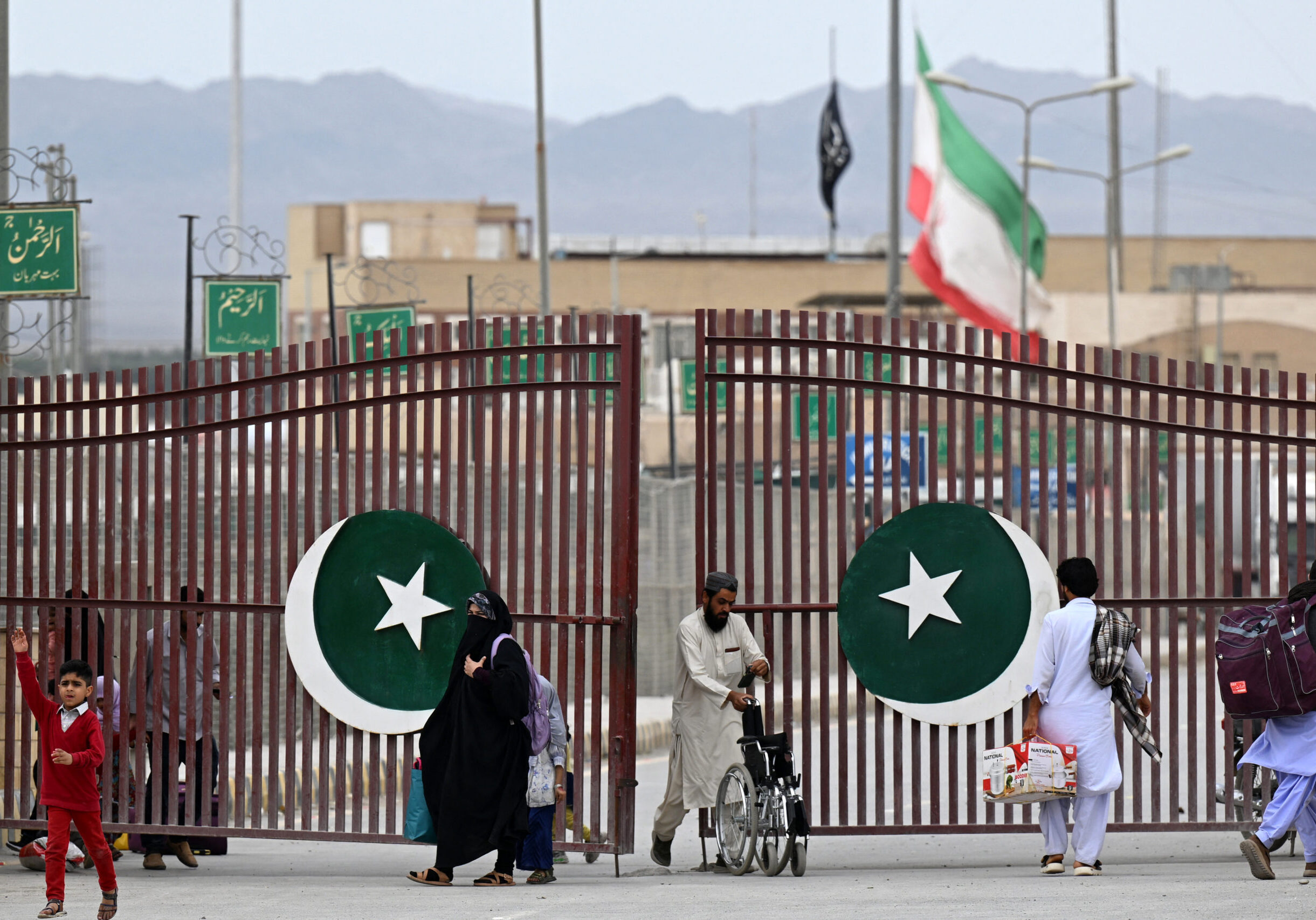 Pakistanis walk across the Taftan border as they return from Iran, in Balochistan province, on March 9, 2026 amid ongoing US-Israel strikes on Iran. (Photo by Banaras KHAN / AFP via Getty Images)